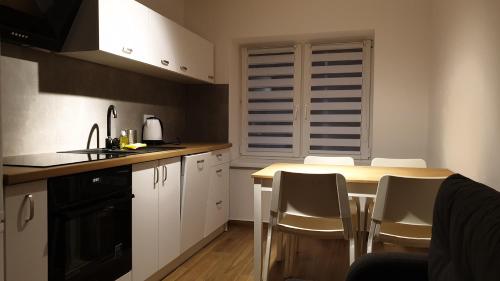 a kitchen with white cabinets and a table with chairs at Dom Pod Groniem in Rzyki