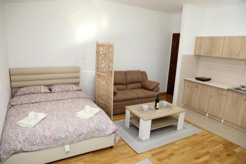 una camera con letto, divano e tavolo di Apartman Frida a Nikšić