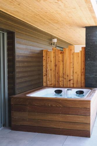 a bath tub in a room with a wooden wall at L'Argalyde Esprit Pyrénées Wellness & Cycling in Ayzac-Ost