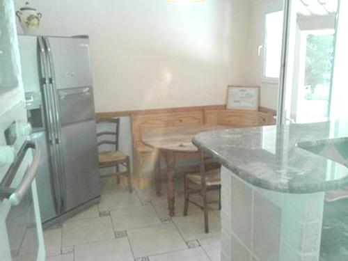 eine Küche mit einem Kühlschrank aus Edelstahl und einem Tisch in der Unterkunft Villa de 4 chambres avec piscine privee jardin amenage et wifi a Malaucene in Malaucène