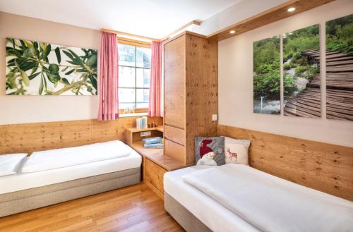 two beds in a room with wooden walls and windows at Fewo-Obertauern-Steinadler in Obertauern