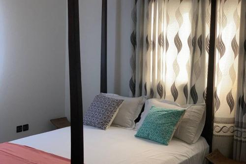 ein Bett mit einem schwarzen und weißen Himmelbett mit Kissen in der Unterkunft Villa Luxury Baguida in Lomé