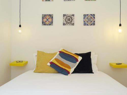 a bedroom with a white bed with pillows and pictures on the wall at Mouraria lovers cozy bright apartment in Lisbon