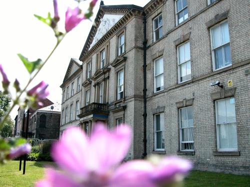 a large brick building with pink flowers in front of it at Park Hotel & Apartments in Hull