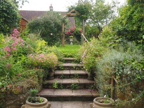 a garden with a bunch of flowers and stairs at Clare Cottage in Sherborne
