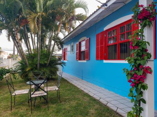 a blue building with red windows and a table and chairs at Pequi hostel in Florianópolis