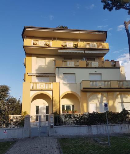 a yellow building with a gate in front of it at Apartamento Vittoria Marina di Pietrasanta in Pietrasanta