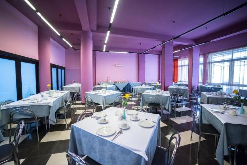 a restaurant with white tables and chairs and purple walls at La Piramide in Roccalumera
