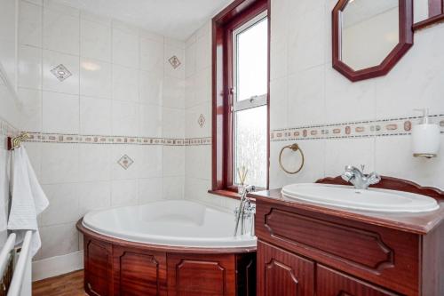 a bathroom with a tub and a sink and a mirror at Spacious 5 Bedroom House in Gravesend in Gravesend