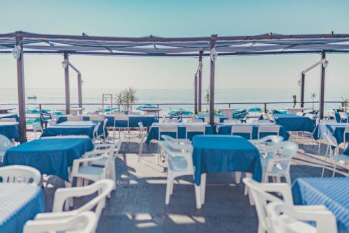 a group of tables and chairs with the ocean in the background at La Piramide in Roccalumera