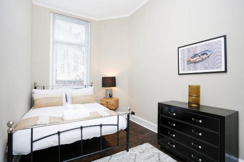 um quarto com uma cama com uma cómoda preta e uma janela em ALTIDO Modern 1-BR Apartment in Trendy Stockbridge em Edimburgo