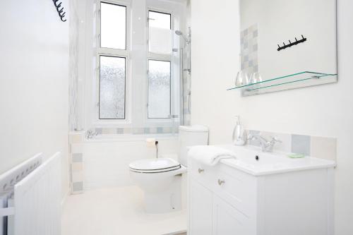 a white bathroom with a toilet and a sink at ALTIDO Modern 1-BR Apartment in Trendy Stockbridge in Edinburgh