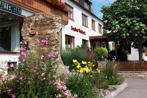 Landhotel Waldeck - Ihr Urlaubshotel in der Natur في Fremdingen: حديقة من الزهور أمام المبنى