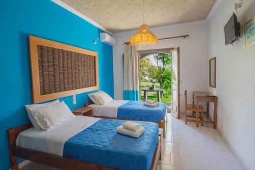 two beds in a room with a blue wall at Villa Spyridoula studios on the Beach in Sidari
