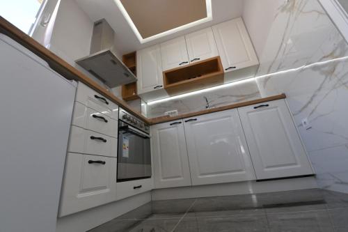 a white kitchen with white cabinets and a sink at Family apartman Bijeljina in Bijeljina