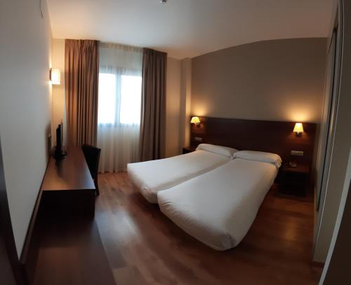 a bedroom with a large white bed and a window at Hotel Pago del Olivo in Simancas