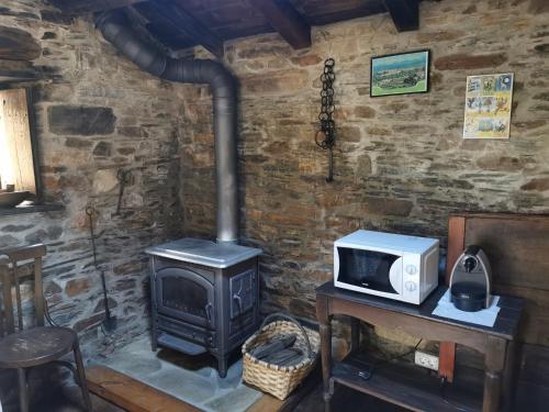 una cocina con microondas y estufa en Habitación Cuadruple con derecho a Barbacoa y patio, en Navia de Suarna