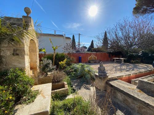 een tuin met een stenen patio met een bank bij Le Clos de L'Isle in Arles