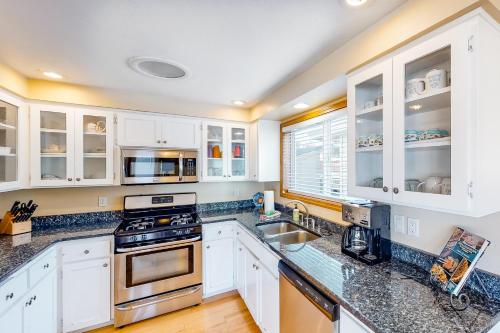 a kitchen with white cabinets and granite counter tops at Oceanfront Solitude in Gleneden Beach