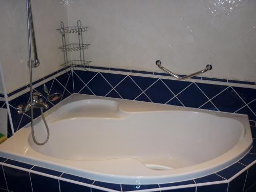 a white bath tub in a bathroom with blue tiles at Nueva Fiesta Apartment in Mariánské Lázně