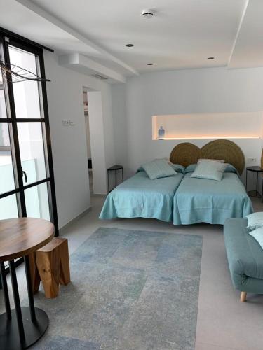 a white bedroom with a bed and a table at Aparthotel El Cargol in L'Escala