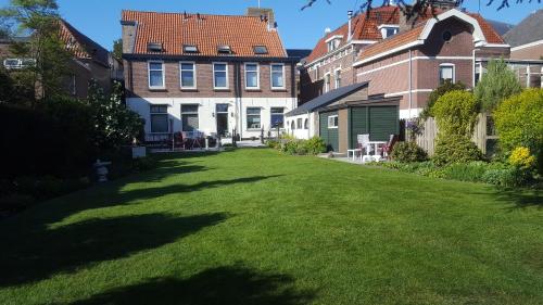 un grand jardin avec des bâtiments et une pelouse dans l'établissement BB Salem, à Strijen