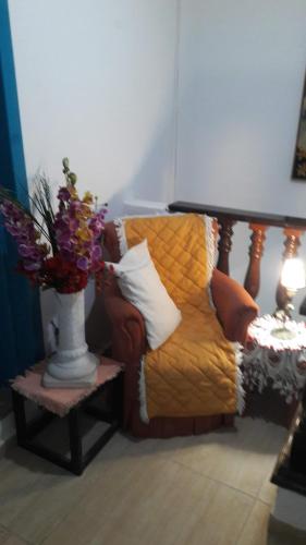a vase of flowers on a table next to a bed at The House Pousada e Hospedagem Enseada- Guarujá in Guarujá