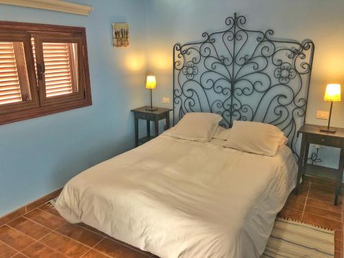1 dormitorio con cama blanca y cabecero de metal en CASA ABUELA MINA, en Lomo de Arico