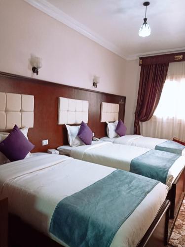 two beds in a hotel room with purple pillows at Grand Hotel Ras Elbar in Ras El Bar