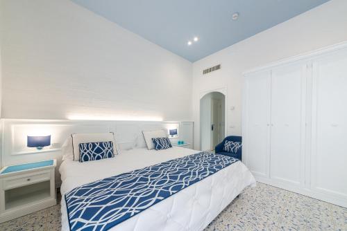 a white bedroom with a blue and white bed at Hermitage Resort & Thermal Spa in Ischia