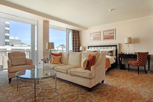 a living room with a bed and a couch and a table at Taj Hotel Cape Town - luxury 5 star suites - very spacious with kitchenette, Lions Head views in Cape Town