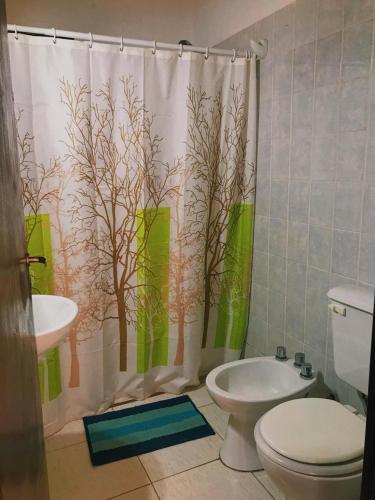 a bathroom with a shower curtain with a toilet and a sink at Los Coirones in Potrerillos