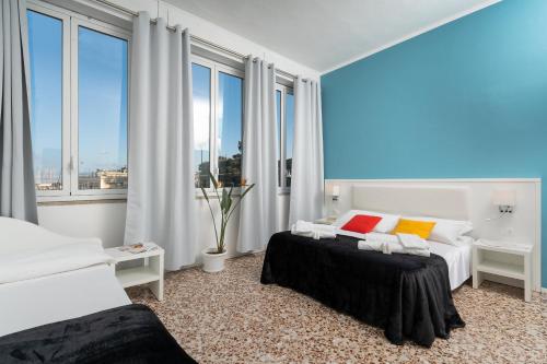 a bedroom with two beds and large windows at Regina Margherita - Bed and Breakfast & Rooftop Lounge Bar in Siracusa