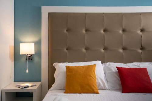 a bed with a large padded headboard and two pillows at Regina Margherita - Bed and Breakfast & Rooftop Lounge Bar in Siracusa