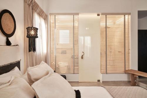 a bedroom with a bed with white pillows and a window at Volcano Luxury Suites Milos - Adults Only in Paliochori