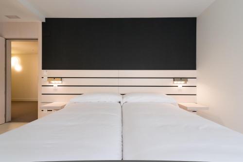 a bedroom with two white beds and a flat screen tv at Hotel Boreal Viento Norte in Burgos