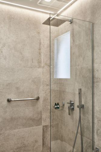 a shower stall with a glass shower door at Volcano Luxury Suites Milos - Adults Only in Paliochori