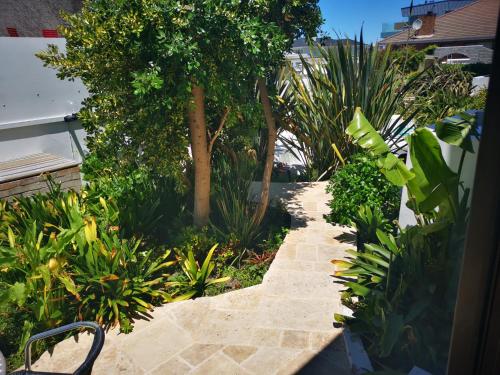 a garden with a stone walkway with trees and plants at Misty Waves Boutique Hotel in Hermanus