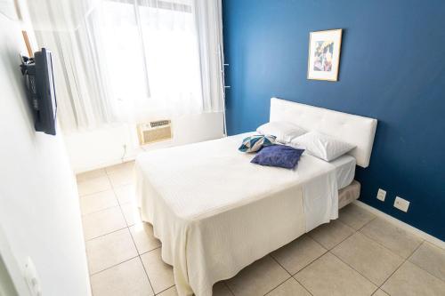 1 dormitorio con 1 cama grande y pared azul en Mc Flats Leblon Inn, en Río de Janeiro