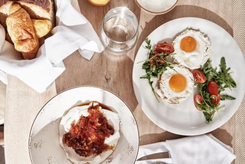 two plates of food with eggs and bread on a table at Volcano Luxury Suites Milos - Adults Only in Paliochori