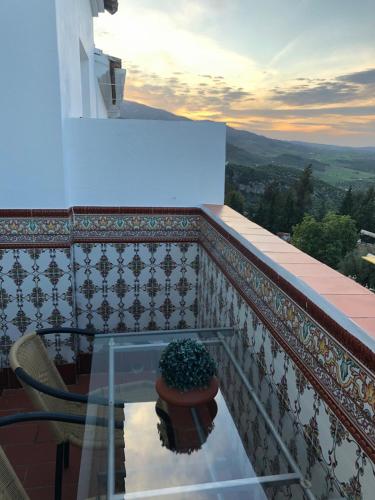a balcony with a glass table and a plant at Casas PARAJE NATURAL in Zahara de la Sierra