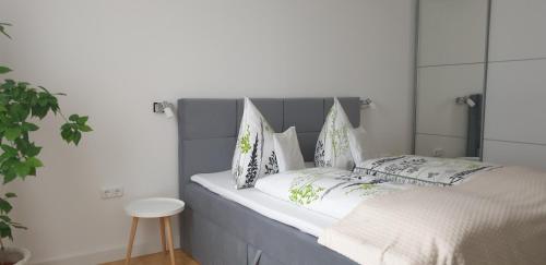 a bed with a gray headboard and pillows on it at Tópart Apartman in Tapolca