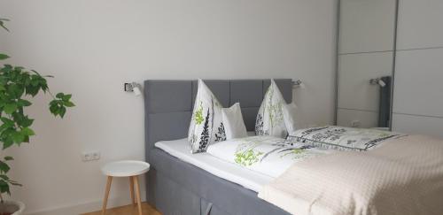 a bed with a gray headboard and pillows on it at Tópart Apartman in Tapolca