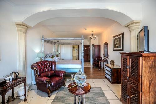 a bedroom with a bed and a chair and a table at Misty Waves Boutique Hotel in Hermanus