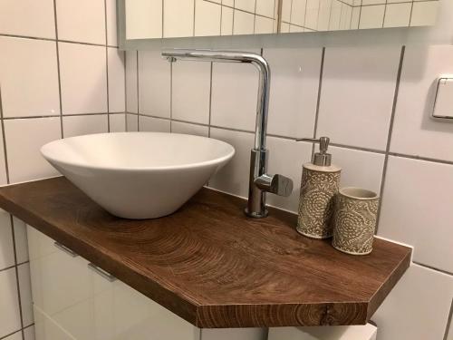 um lavatório branco sobre um balcão de madeira na casa de banho em FeWo Khuki em Leipzig