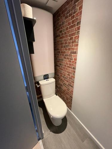 a bathroom with a toilet and a brick wall at Logements équipés à Onnaing avec espace Balneo en OPTION proche Toyota, autoroute et Valenciennes in Onnaing