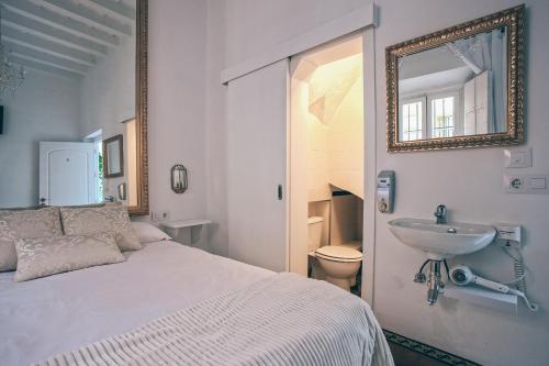 um quarto com uma cama, um lavatório e um espelho em Alcázar de María em Sevilha