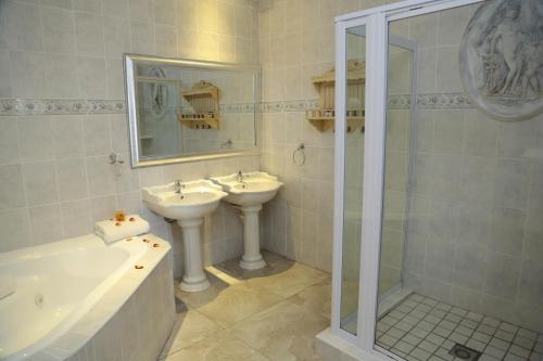 a white bathroom with two sinks and a shower at Misty Waves Boutique Hotel in Hermanus