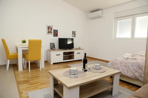a living room with a bed and a table and a tv at Apartman Frida in Nikšić
