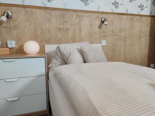 a bedroom with a white bed and a night stand at Penzion Bílá voda in Harrachov